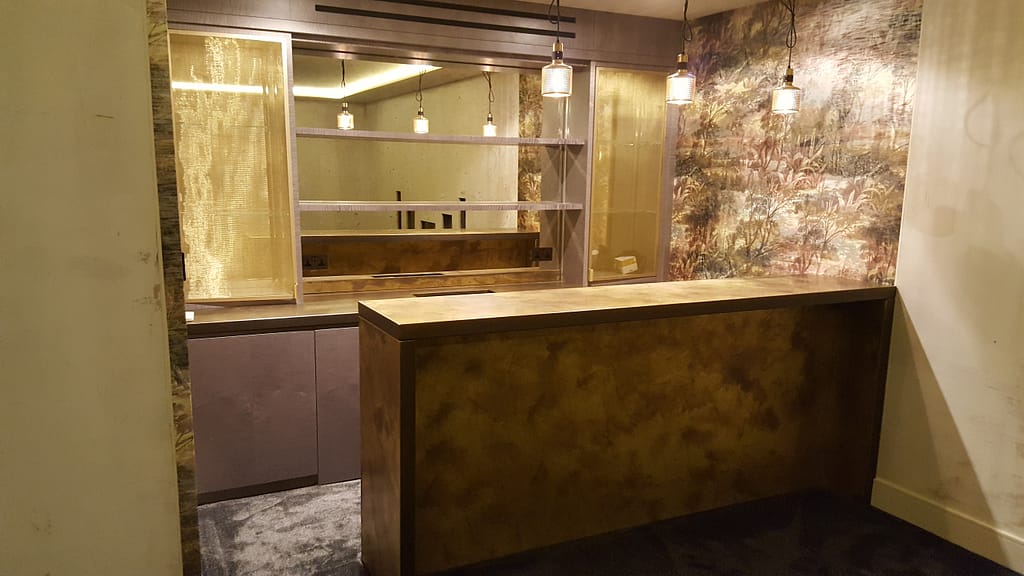 Brass-worktops - Designs 05 Luxury brass worktop with a patinated finish, used as a stylish brass bar counter in a bespoke interior setting with warm lighting.