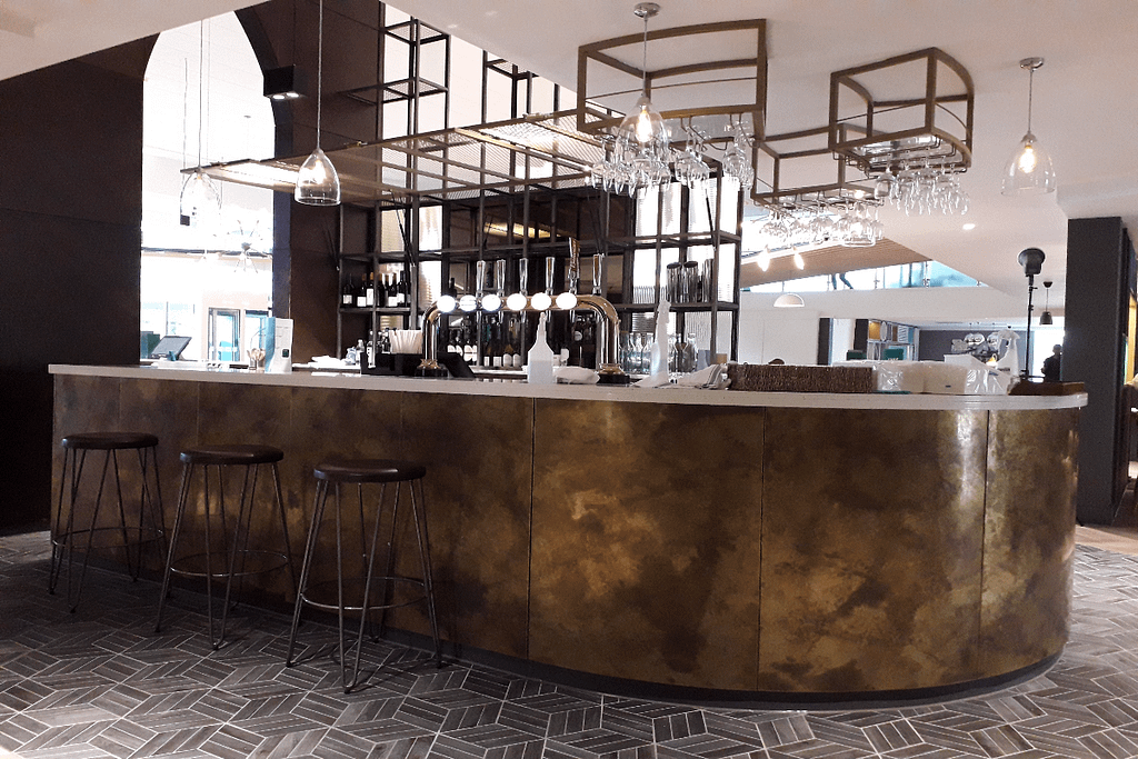 Curved aged brass bar front cladding hospitality interior