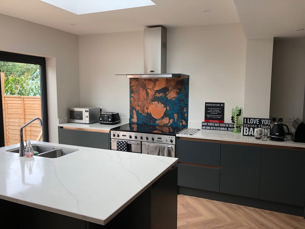 Bespoke Blue Patina Copper Splashback Behind a Stainless Steel Range Cooker - Designs 05 Artisan-crafted blue patina copper splashback installed behind a range cooker, featuring a deep oxidation finish with striking blue and bronze hues.