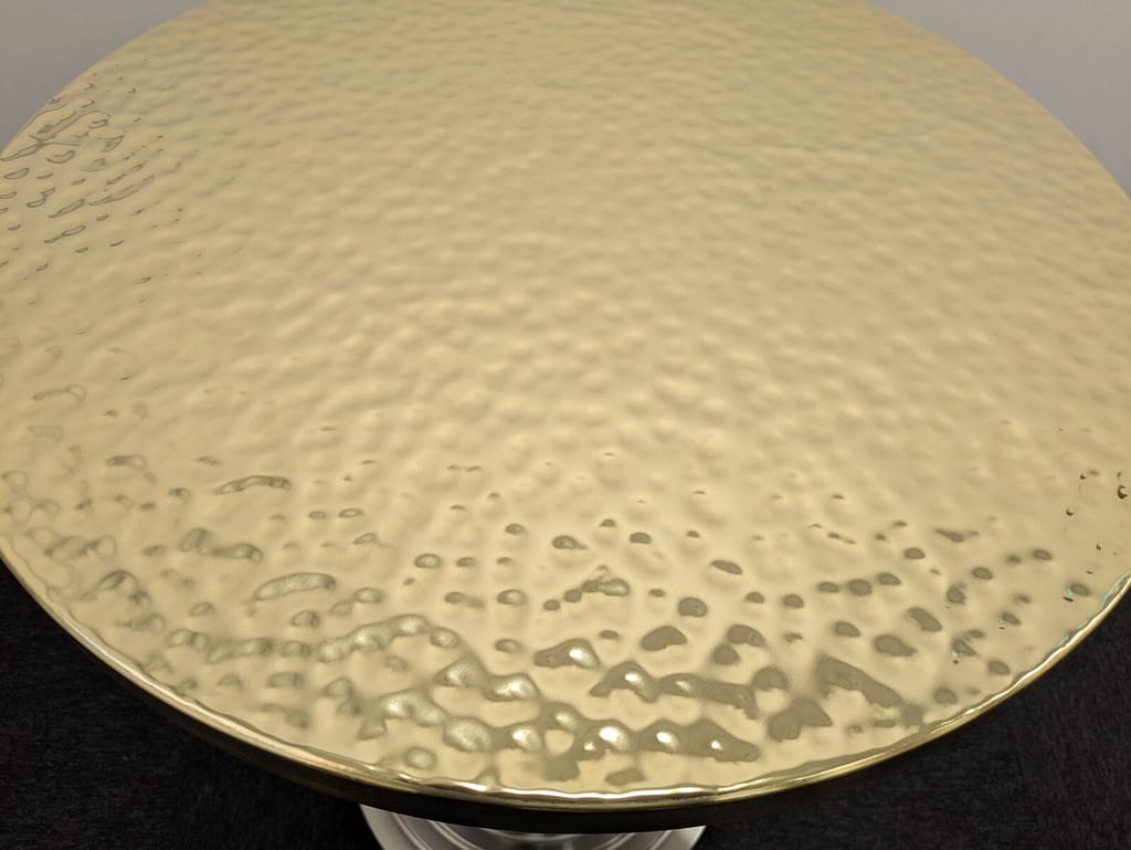 Hammered Brass Table Top – Close-Up Texture & Finish - Designs 05 Close-up of a hammered brass table top, showcasing its hand-crafted texture and reflective golden finish.