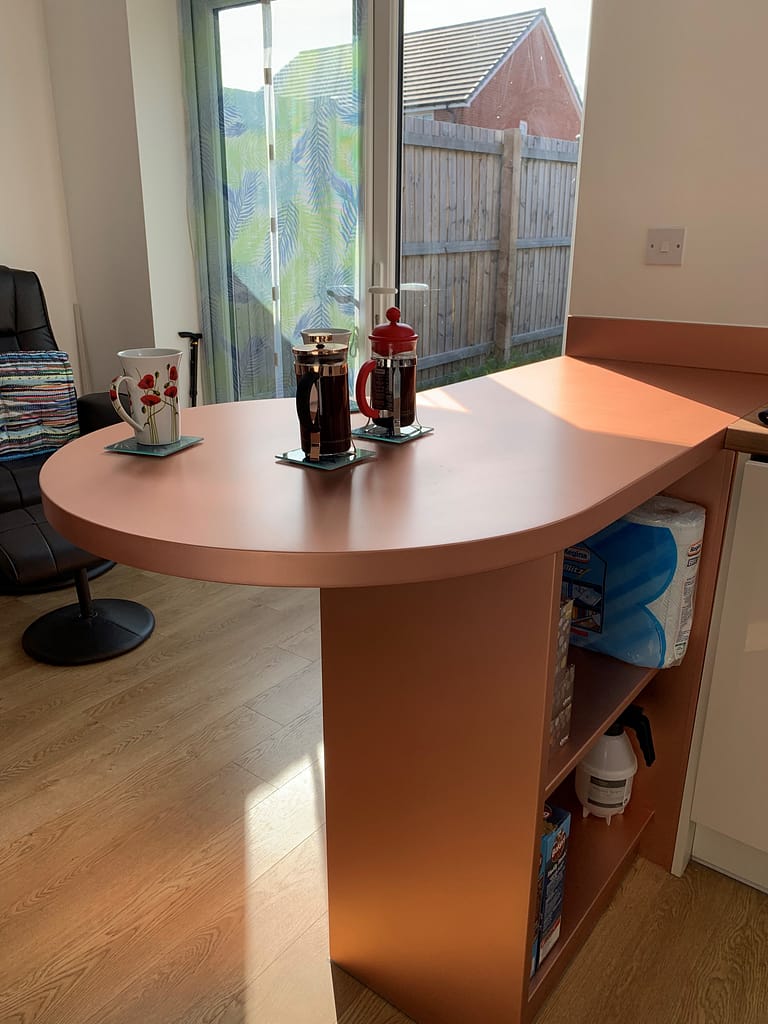 Copper-Breakfast-Bar-and-Base - Designs 05 Custom copper breakfast bar with a smooth, curved design, seamlessly integrated into a compact kitchen space, offering both functionality and a sleek, modern aesthetic.