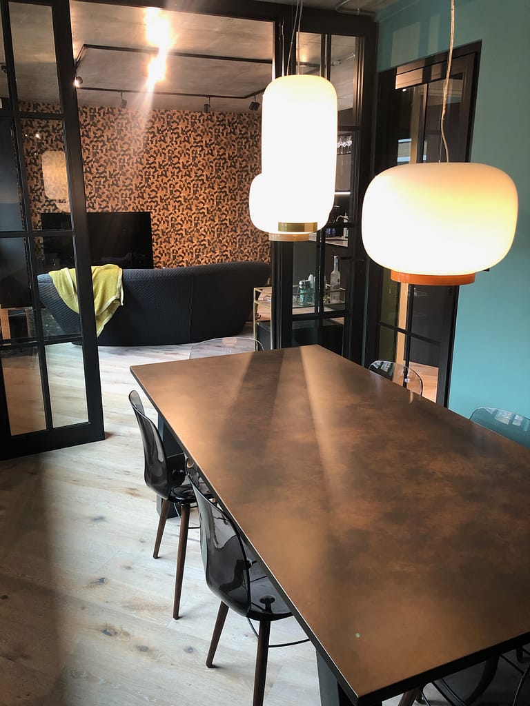 Copper Dining Table Top 6 seat - Designs 05 Dark patinated metal dining table used as a feature piece in an open-plan interior