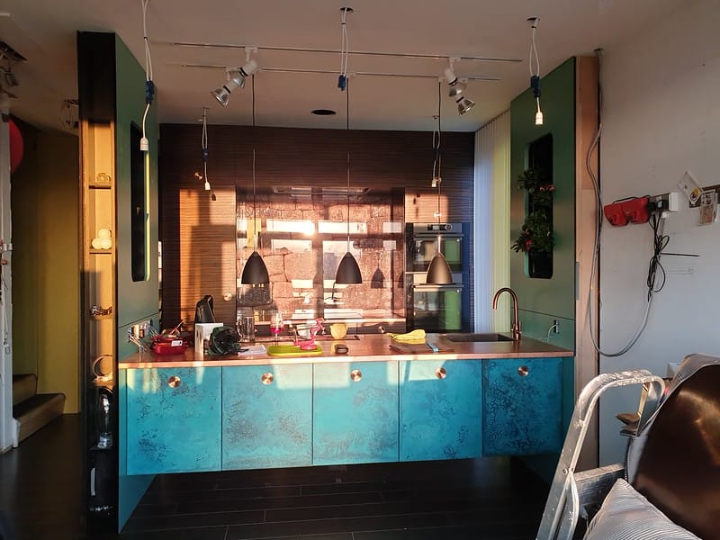 Copper show kitchen - Designs 05 Bespoke copper kitchen worktop with a striking blue patina finish on the cabinetry, creating a bold contrast in a modern open-plan kitchen with pendant lighting.